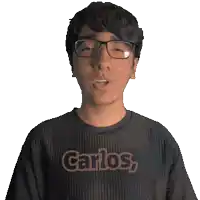 a man wearing glasses and a black shirt with the word carlos on it