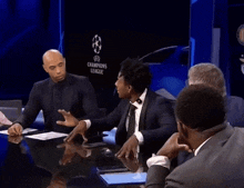 a group of people sitting around a table in front of a champions league logo