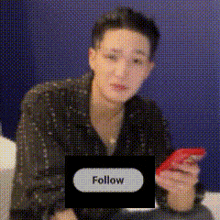 a man is holding a cell phone with a follow button in the corner