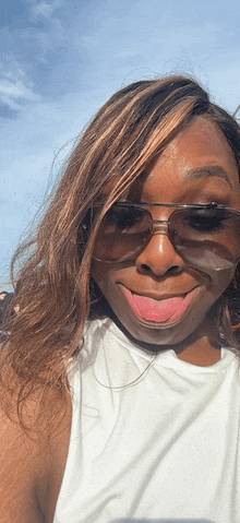a woman wearing sunglasses and a white tank top