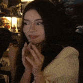 a woman with long dark hair is sitting in front of a microphone and looking at the camera .