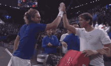 two tennis players high five each other in front of a team euro sign