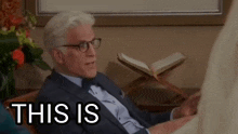 a man in a suit and tie is sitting in a chair with the words this is on the screen .