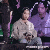 a man in a baseball cap is sitting in front of an lg monitor holding a microphone .