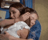 two women hugging each other with one holding the other 's head