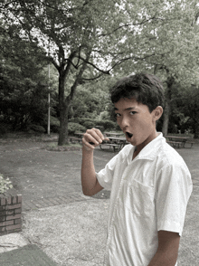 a young boy in a white shirt is eating something