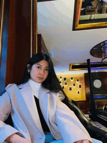 a woman in a white coat is sitting in front of a clock