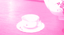 a cup and saucer are on a pink table next to a teapot