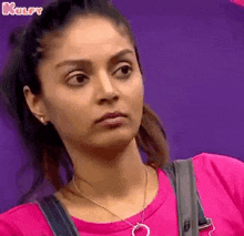 a woman in a pink shirt is making a funny face .