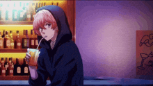 a person in a hoodie drinking through a straw in a bar