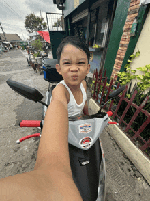 a little boy sitting on a honda scooter
