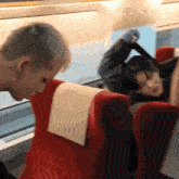 a man sits in a red seat next to a woman