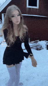 a woman in a black dress is standing in the snow