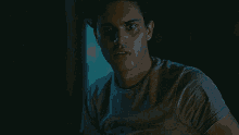 a young man is sitting in a dark room looking at the camera .