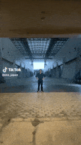 a man is standing in a hallway with a tiktok watermark on the bottom