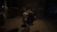 a man is kneeling down in a dark room with a lantern in the background