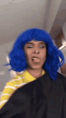 a person wearing a blue wig and a yellow shirt is sticking out their tongue