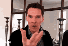 a man is making a funny face while standing in front of a mirror and candlesticks .