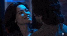 a man and a woman kissing in front of a neon sign that says charles