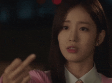 a woman in a pink sweater is pointing her finger at something
