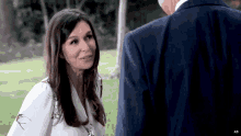 a woman in a white shirt and a man in a blue suit are looking at each other