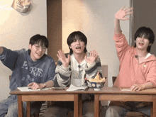 three young men sitting at a table with one wearing a sweatshirt that says paris