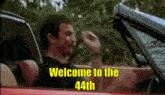 a man driving a car with the words welcome to the 44th on the bottom