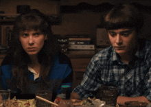 a boy and a girl are sitting at a table eating food