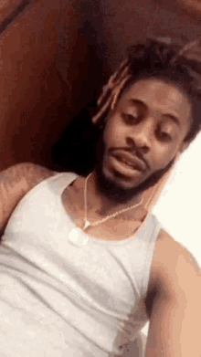 a man with dreadlocks and a beard is taking a selfie with his phone .