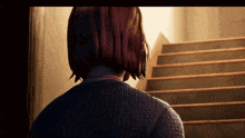 a woman in a sweater is standing in front of stairs