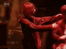 a man in a red costume is hugging another man in a red costume .