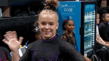 a girl is waving in front of a usa gymnastics core refrigerator