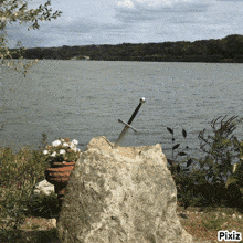 a picture of a sword in a rock by a lake with pixiz written on the bottom