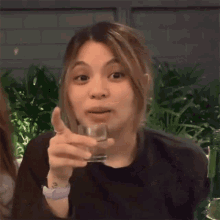 a woman is holding a glass of water in her hand .