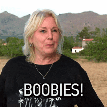 a woman wearing a black shirt with the word boobies on it