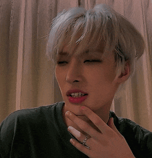 a man with a ring on his finger is covering his mouth with his hand .