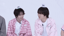 a boy wearing a pink plaid shirt has a name tag on his head that says ' seo '