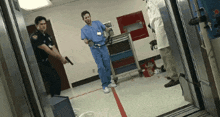 a police officer holds a gun while two doctors stand in a hospital room