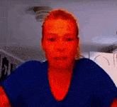 a woman in a blue shirt is making a funny face in a video call .
