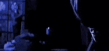 a person is standing in front of a window in a dark room with a blue light behind them .