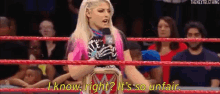 a woman is standing in a wrestling ring with a microphone in her hand and talking into it .