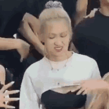 a woman in a white shirt and a black top is making a funny face .