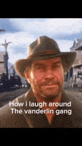 a man wearing a cowboy hat is laughing while standing in a town .