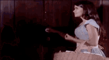 a woman in a blue dress is standing in front of a wooden door .
