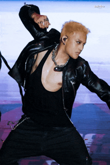 a man wearing a black leather jacket and a black tank top is dancing
