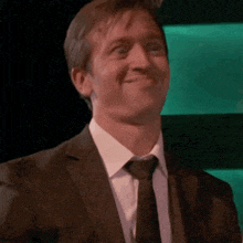 a man wearing a suit and tie is smiling