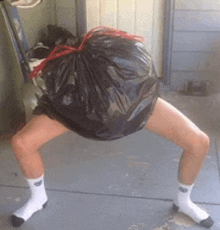 a person wearing white socks is holding a black garbage bag