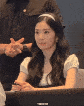 a woman sitting at a table with taek0321 on the bottom