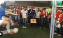 a man is kicking a soccer ball while a crowd watches
