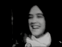 a black and white photo of a woman smiling in a room .